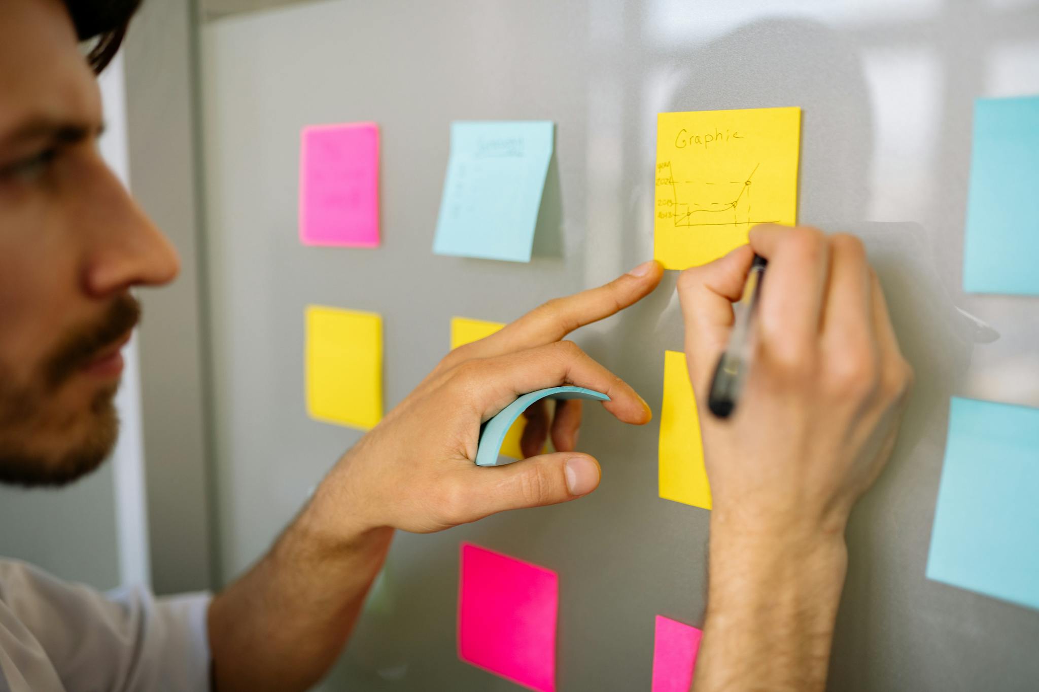 Focused businessman writing ideas on sticky notes for planning and organization.
