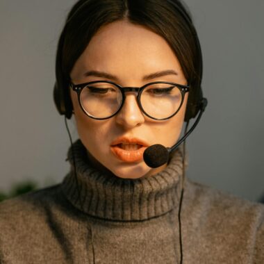 Close-up of a focused call center agent with eyeglasses and headset providing customer support.