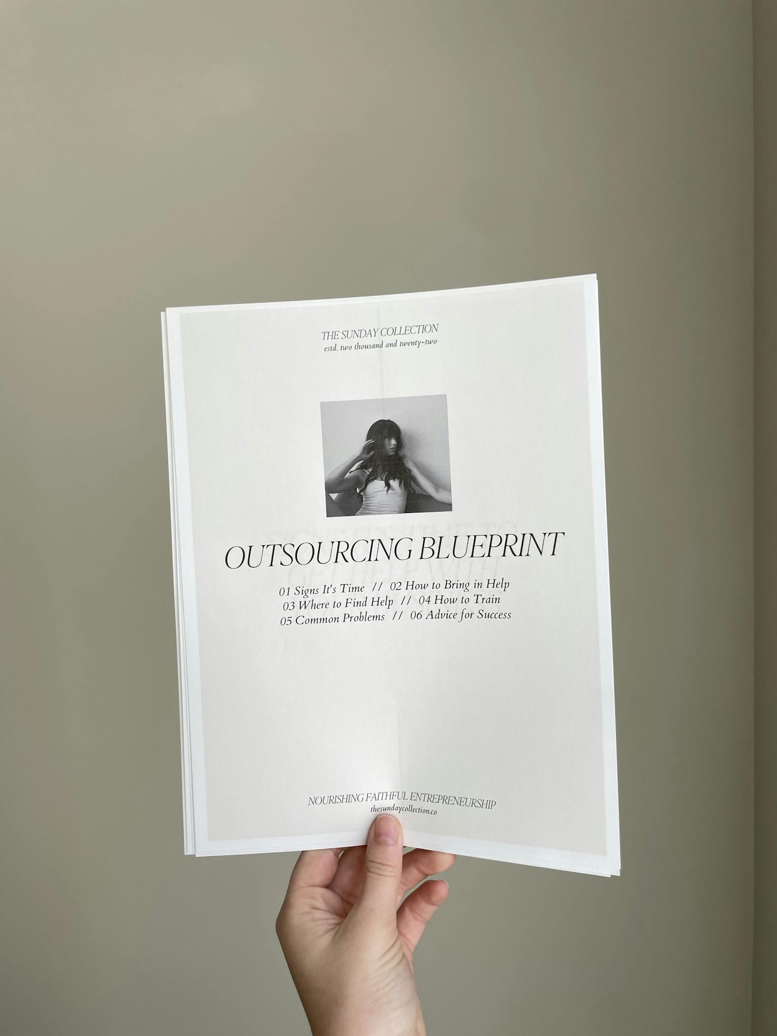 Close-up of a hand holding a business document titled 'Outsourcing Blueprint'.