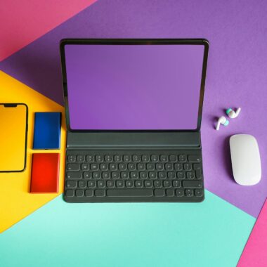 Vibrant flat lay of tablet, smartphone, and mouse on colorful background.